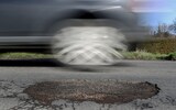 A car driving past a pothole