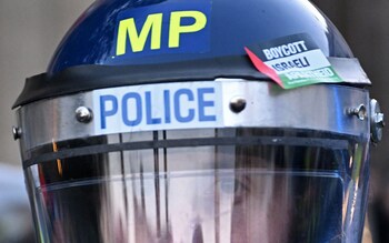 A police officer inadvertently wears an anti-Israeli sticker on his helmet during a march for palestine