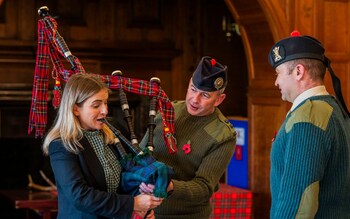 Abigail Buchanan attempts the bagpipes under the guidance of Capt Ross McCrindle and Senior Pipe Major WO1 Colin Simpson