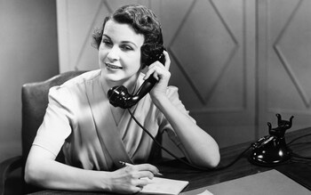 Woman talking on phone at desk (B&W)