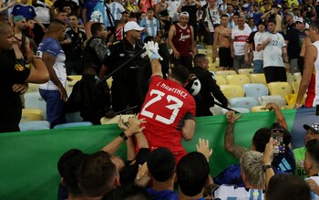 Argentina's Emiliano Martinez and teammates react as fans clash with security staff in the stands causing a delay to the start of the match